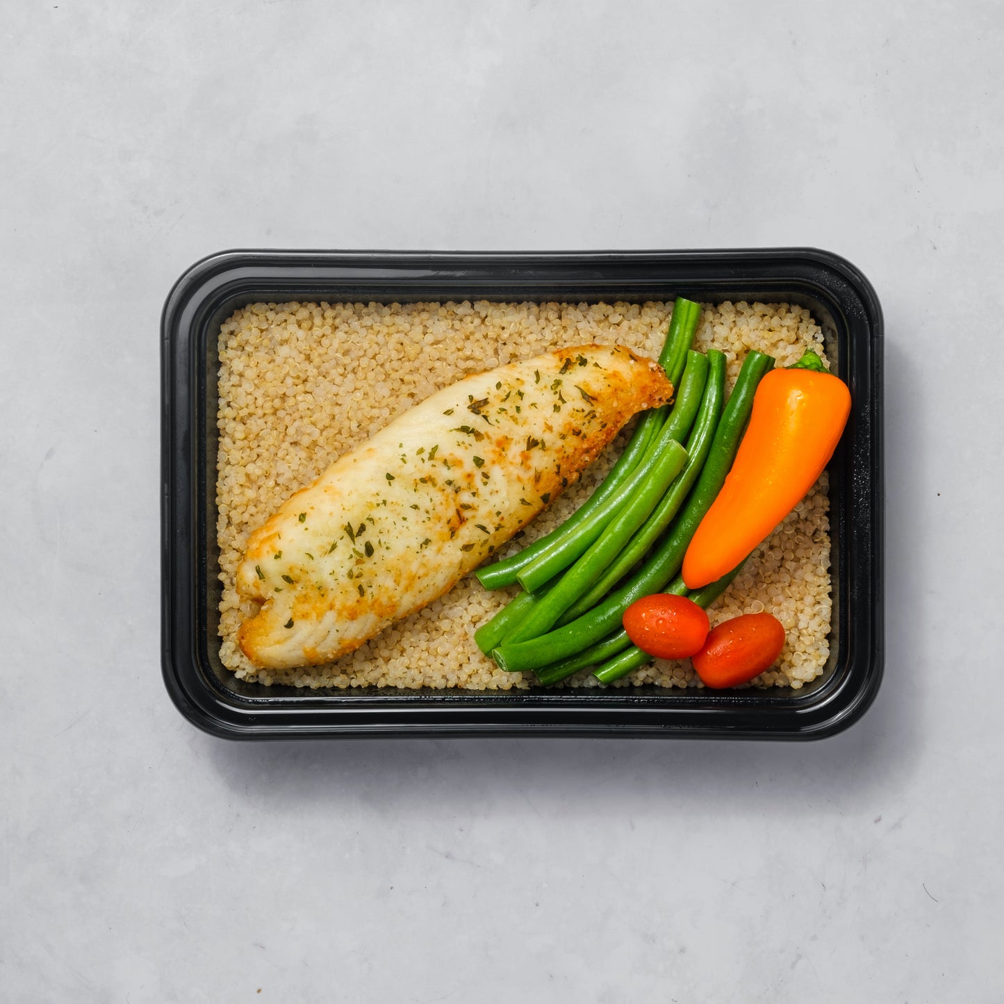 Tilapia sazonado con especias, quinoa orgánica y ensalada.